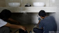 Beberapa pekerja tengah menyelesaikan instalasi di dalam toilet.