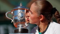Ostapenko mencium trofi Prancis Terbuka. Gonzalo Fuentes/Reuters.