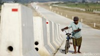 Seorang warga menuntun sepedanya di Tol Pejagan-Pemalang seksi III.