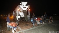 Para pekerja melakukan pengecoran jalan.