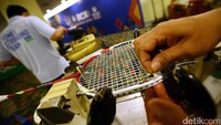 Seorang petugas reparasi memasangkan senar raket milik salah satu atlet. 