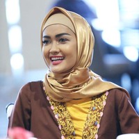 Penampilan Jupe yang tersenyum renyah dalam jilbab satin warna keemasan ketika sedang menjalankan ibadah umrah. Foto: Instagram @juliaperrezz