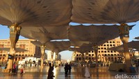 Jika kita memunggungi sunrise, kita akan melihat cahayanya menyorot ke marmer lantas memantul indah ke arah payung. Semburat matahari terbit ini membuat suasana makin cantik di teras masjid (Fitraya/detikTravel)