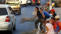 Pemburu koin dengan sigap mengambil uang-uang pemberian pengendara.