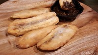 Sebagai menu pembuka, Anda bisa cicip Pisang Garing Sambal. Lembaran pisang kepok goreng tepung ditemani semangkuk sambal roa yang pedas gurih.
