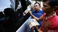 Seorang warga menukarkan uang pecahan Rp 5.000 dan Rp 2.000.