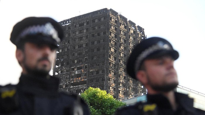 Police officers stand in front of the The Grenfell Tower block that was destroyed by fire, in north Kensington, West London, Britain June 16, 2017. REUTERS/Toby Melville