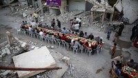 Warga Damascus, Suriah, menggelar buka puasa di antara puing-puing bangunan, Senin (19/6). REUTERS/Bassam Khabieh.
