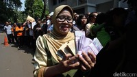 Seorang warga memperlihatkan uang baru yang diperolehnya di depan kamera.