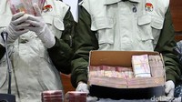 Petugas KPK menunjukkan tumpukan uang pecahan Rp 100.000 di dalam kardus.