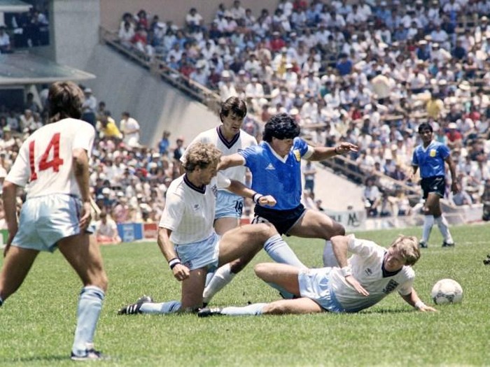 Argentinian midfielder Diego Maradona (C) dribbles past three English defenders on June 22, 1986 in Mexico City during the World Cup quarterfinal soccer match between Argentina and England. Maradona scored two goals, the first one with his left hand as he jumped for the ball in front of goalkeeper Peter Shilton, as Argentina beat England 2-1. / AFP PHOTO / STAFF