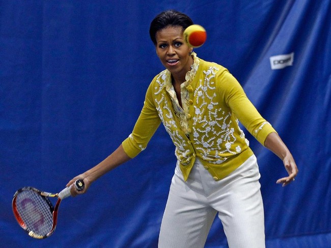 Michelle Obama menerima servis dari lawan mainnya saat bermain tenis di sela kunjungannya ke sebuah sekolah di Washington, 2012, lalu. Ia memukau dengan cardigan kuning berhiaskan motif floral. (Foto: Getty Images)