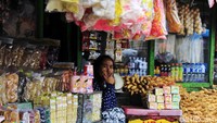 Seorang pedagang menunggu pembeli di kiosnya.