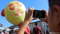 Seorang anak mengabadikan balon yang akan diterbangkan.