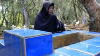 Seorang warga berdoa di depan makam keluarga.