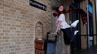 Menuju Hogwarts, seorang wanita berpose di Platform 9 3/4 Stasiun King Cross di London.