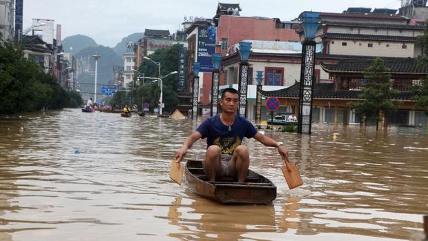 Salah satu warga Guangxi menyeberangi banjir dengan kapal kayu