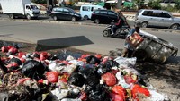 Seorang pemulung mengais botol dan kadus bekas di tumpukan sampah.