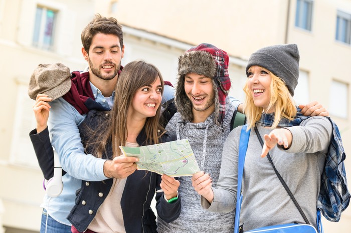 ilustrasi traveler Group of young hipster tourists friends cheering with city map in the old town - Travel lifestyle concept with happy people having fun together - Winter fashion clothing wears with neutral color tones