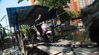 Seorang pengendara motor memanfaatkan perahu eretan untuk menyebrang sungai di kawasan Pademangan Barat, Jakarta, Selasa (4/7/2017).