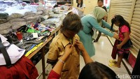 Calon pembeli mencoba baju seragam sekolah yang dijual di salah satu toko di Pasar Baru, Jakarta, Minggu (4/7).