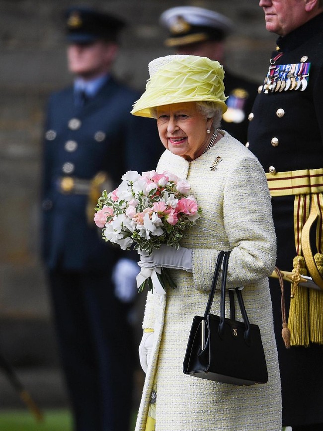 Handbag atau tas tangan mungil berwarna hitam juga menjadi fashion item wajib sang Ratu. Diketahui, Ratu tak pernah ganti model tas selama 60 tahun terakhir. Adalah brand Inggris bernama Launer yang memproduksi tas favorit Ratu. Foto: Jeff J Mitchell/Getty Images