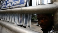 Seorang warga mengintip suasana di dalam kompleks bangunan dari balik pagar.