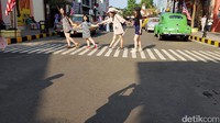 Para wisatawan ini pun asyik-asyik saja foto di tengah jalan. Bahkan mereka bergaya bergandengan tangan bak sedang menyeberang jalan betulan (Budi Sugiharto/detikTravel)