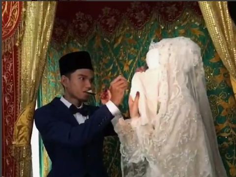 Muzammil dan istri nampak malu-malu saat duduk di pelaminan.