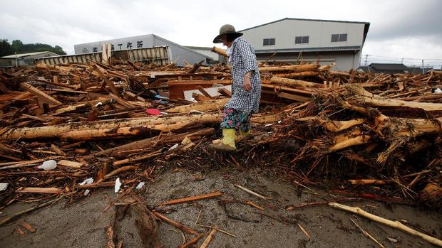 Warga setempat berjalan di antara puing-puing yang terbawa arus banjir