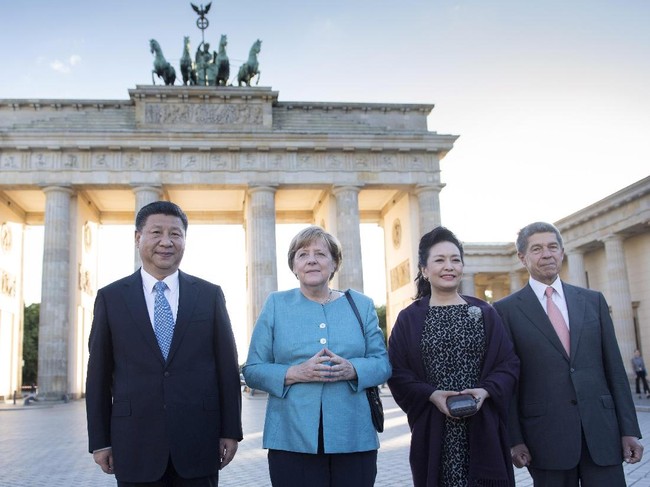 Sebelum ke Hamburg, Peng Liyuan dan suaminya sempat menyambangi Berlin. Berfoto di depan Gerbang Brandenburg yang ikonis itu bersama Kanselir Jerman, ia mengandalkan dress bermotif tutul yang dipadu dengan selendang ungu. (Foto: Getty Images)