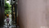 Beberapa anak melintas di gang yang terendam banjir.