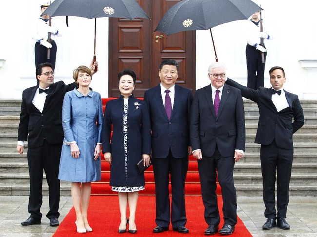 Saat bertemu Presiden Jerman Frank-Walter Steinmeier dan istrinya, Peng Liyuan mengenakan dress putih bermotif floral berbalut coat biru navy yang dipercantik dengan bros bernuansa oriental. (Foto: Getty Images)