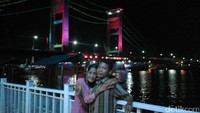 Dua sejoli beda usia itu foto bersama dengan latar Jembatan Ampera. Dalam foto itu Nenek Rohaya terus memeluk erat suaminya. 