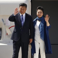 Peng Liyuan tiba dalam  balutan atasan dan celana panjang, serta pointed heels serba putih yang dipadu dengan coat dan syal biru mencolok. (Foto: Getty Images)