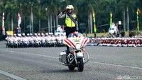 Salah satu personel tampil berdiri di atas motor besar sambil berpose hormat.
