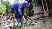 Seorang petugas Sudin Tata Air DKI Jakarta membersihkan sampah yang menyumbat saluran air.