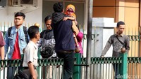 Sambil menggendong putrinya, seorang penumpang melompati pagar stasiun.