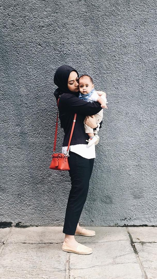 Monokrom menjadi gaya hijab andalan Ayudia Bing Slamet saat berpergian. Seperti kali ini ia tampil stylish dalam setelan blouse modifikasi hitam putih dan celana lurus. Tentunya sepatu beralas datar lebih nyaman dipakai saat berpergian dengan anak. Foto: Dok. Instagram @ayudiac