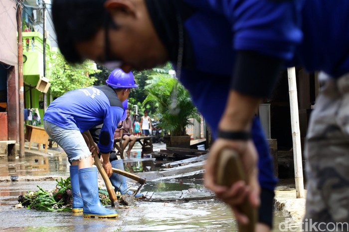 Banjir yang melanda Cipinang Melayu, Jakarta Timur, mulai surut. Petugas Sudin Tata Air DKI Jakarta alias Pasukan Biru terjun ke lokasi untuk membersihkan lumpur sisa banjir.