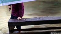Seorang warga melintas di jalan yang terendam banjir. Sebelumnya banjir setinggi 1 meter menggenangi kawasan tersebut.