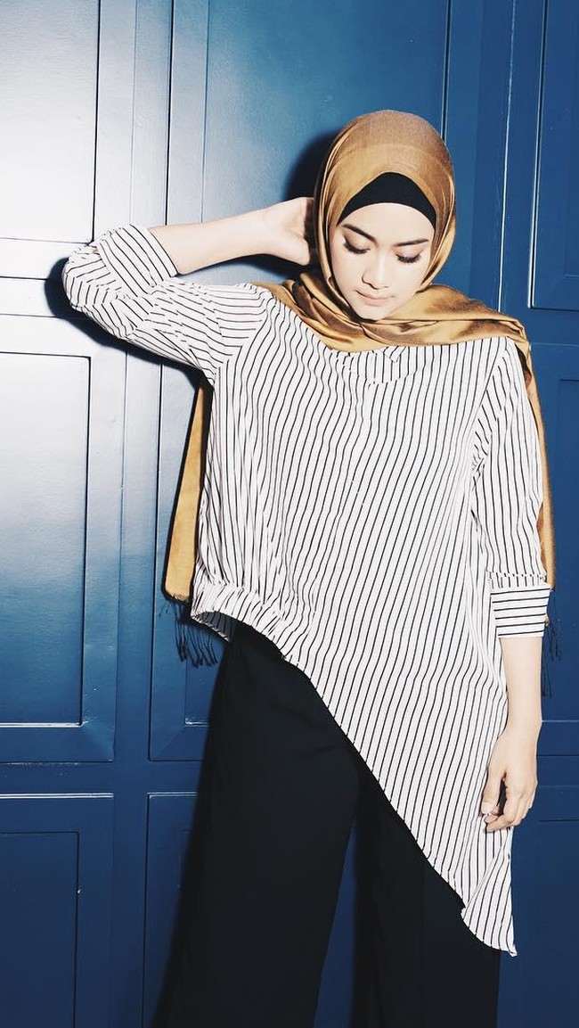 Striped blouse dipilih Ayudia Bing Slamet untuk tampil modis dengan perpaduan celana palazzo hitam. Sementara kerudung warna emas memberikan kesan elegan. Foto: Dok. Instagram @ayudiac