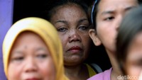 Seorang ibu menangis melihat rumahnya digusur.