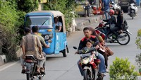 Pengendara motor yang membawa penumpang anak kecil dan tak mengenakan helm ini menerobos rambu larangan berputar arah.