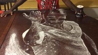 Allan Pachino Wallace membuat lukisan Salt Bae dengan garam. Di atas meja berwarna cokelat tua terlihat pria sedang menaburi garam. Mirip gak? (Foto: Istimewa)