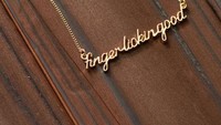 Ada juga kalung bertuliskan Finger Lickin Good. Kalung kabarnya berlapis emas. (Foto: Istimewa)