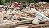 Anak-anak bermain di puing-puing bangunan.