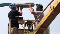 Dengan menggunakan tangga hidrolik, pekerja mengganti lampu yang putus.