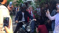 Ia tampak mengendarai motor kala memasuki area acara.