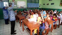 Guru memberikan pertanyaan kepada siswa. Sementara para siswa yang mengetahui jawabannya langsung mengacungkan jari.
